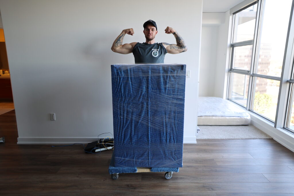 Skilled and knowledgeable movers, with extra muscles! Qshark Moving Employee showing off his packing skills of a dresser and flexing muscles during a local move in Orange County. Double Drive Time Specialists