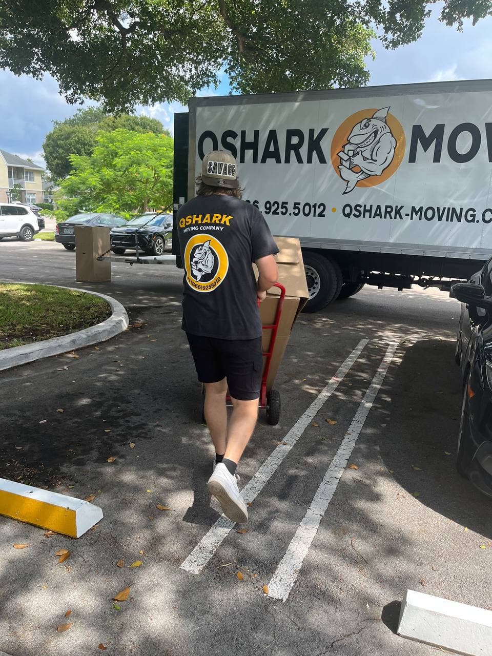 Qshark mover carrying boxes near moving truck in Los Angeles