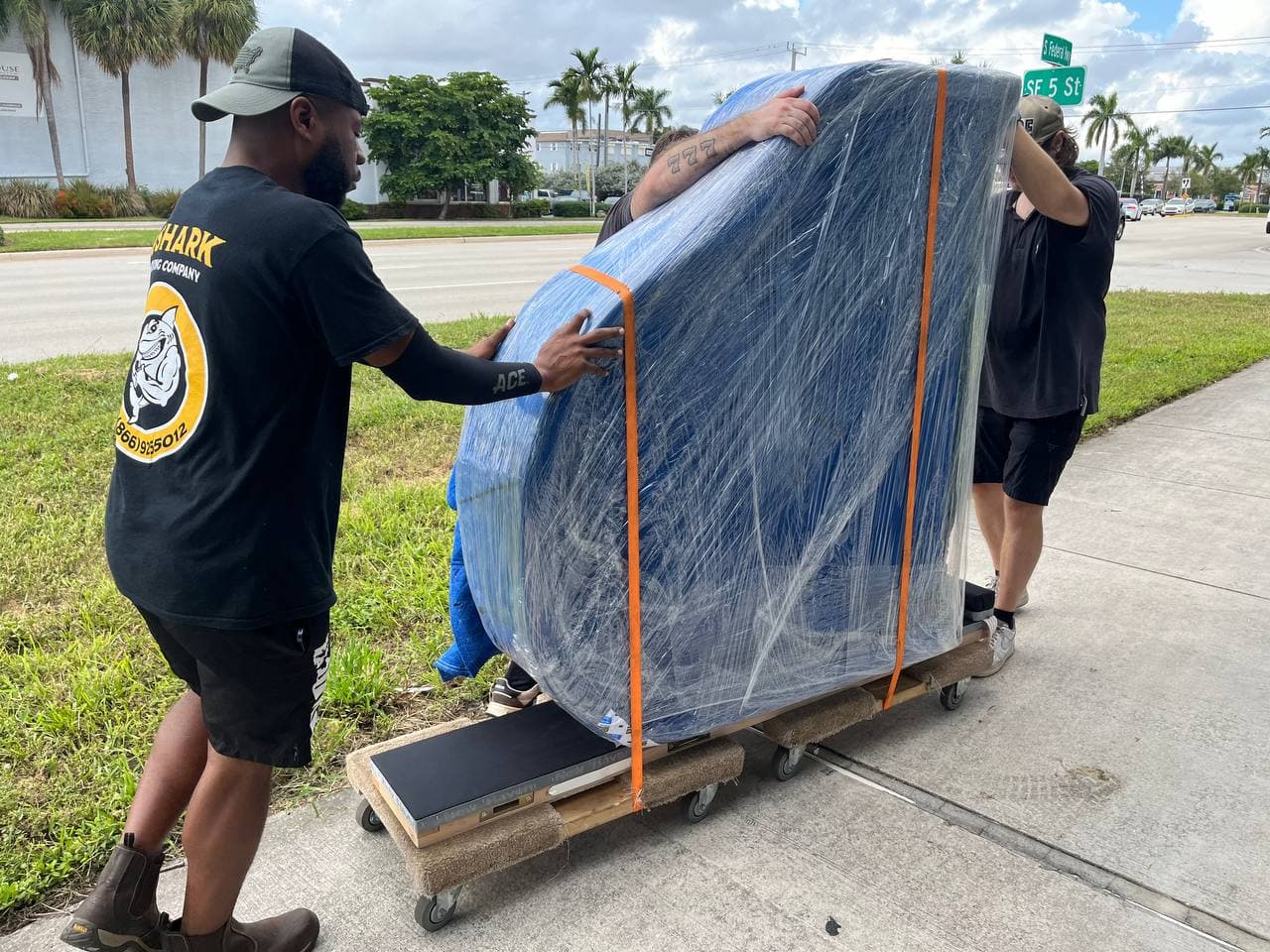 Professional movers handling bulky items on dolly