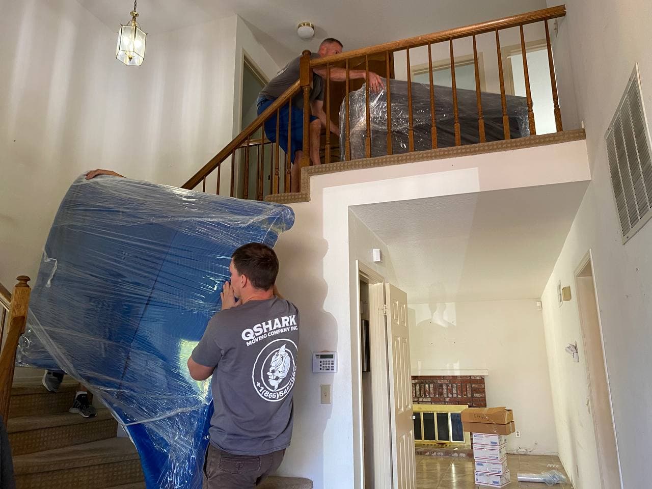 Movers carrying large wrapped furniture upstairs